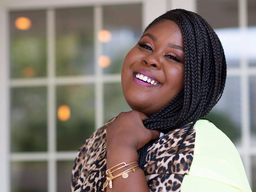 Raven Goodwin smiling into the camera, wearing her hair braided.