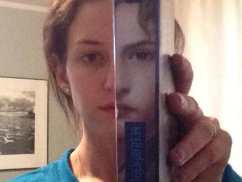 A woman holding up a book cover that looks like her face