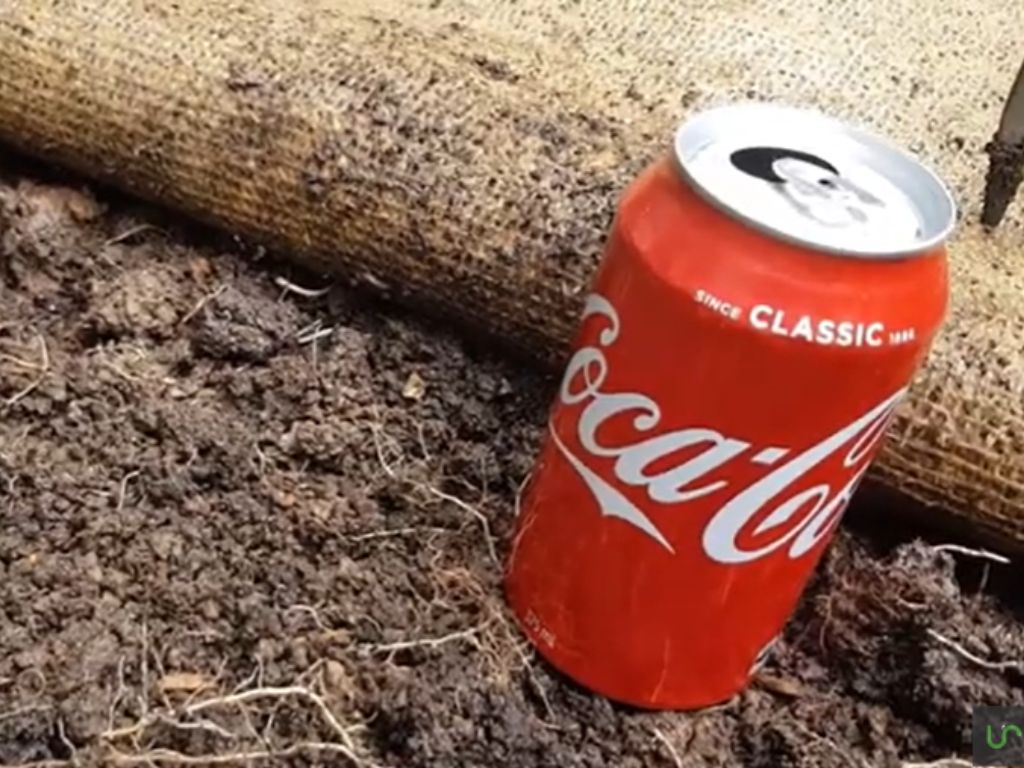 A can of Coca-Cola on a dirt floor