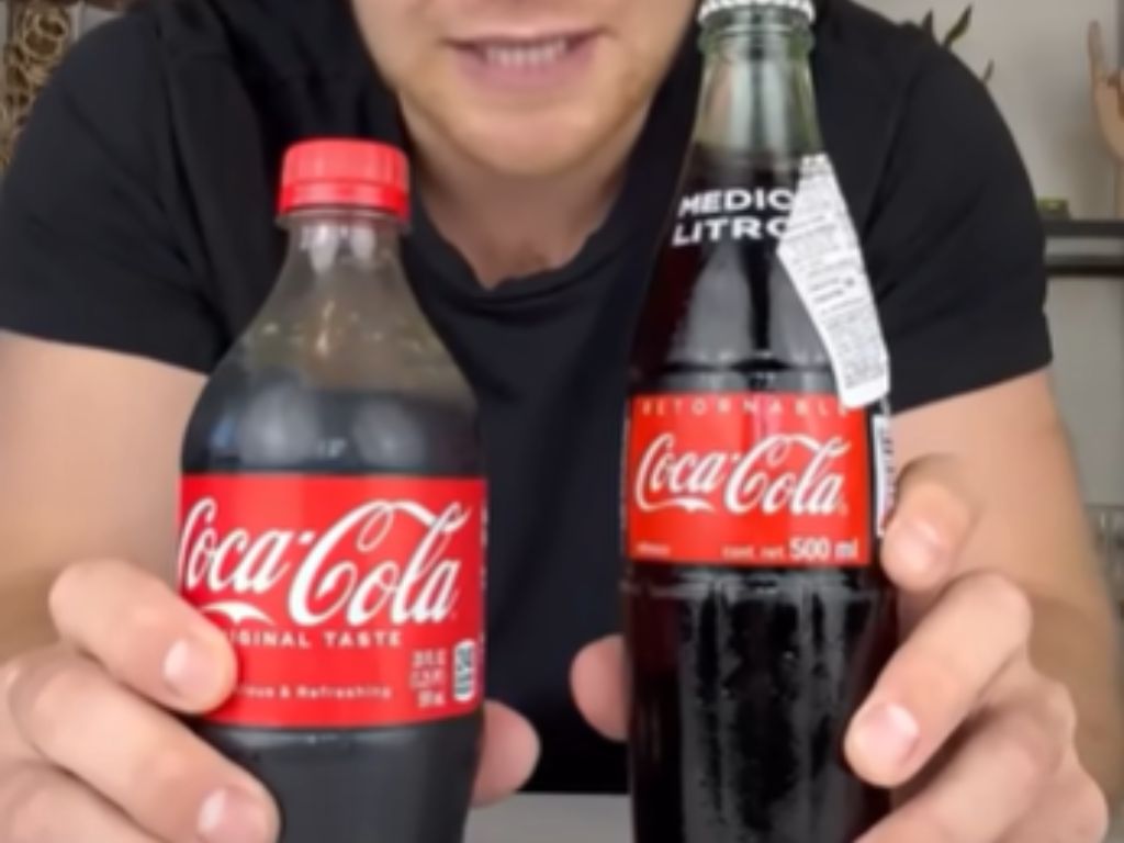 A man holding two bottles of Coca-Cola