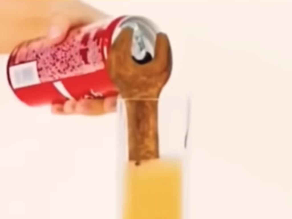 Coca Cola poured into a cup with a rusty wrench in it