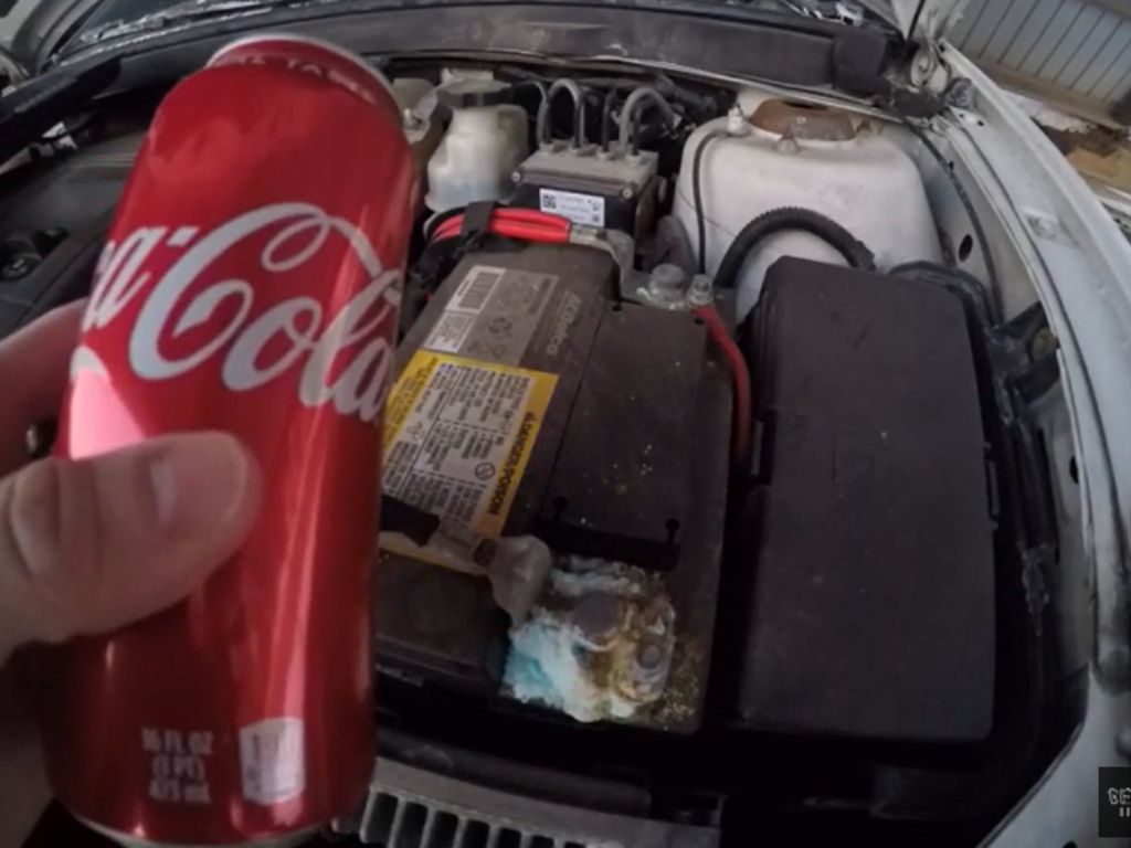 A can of Coca Cola in front of a car battery