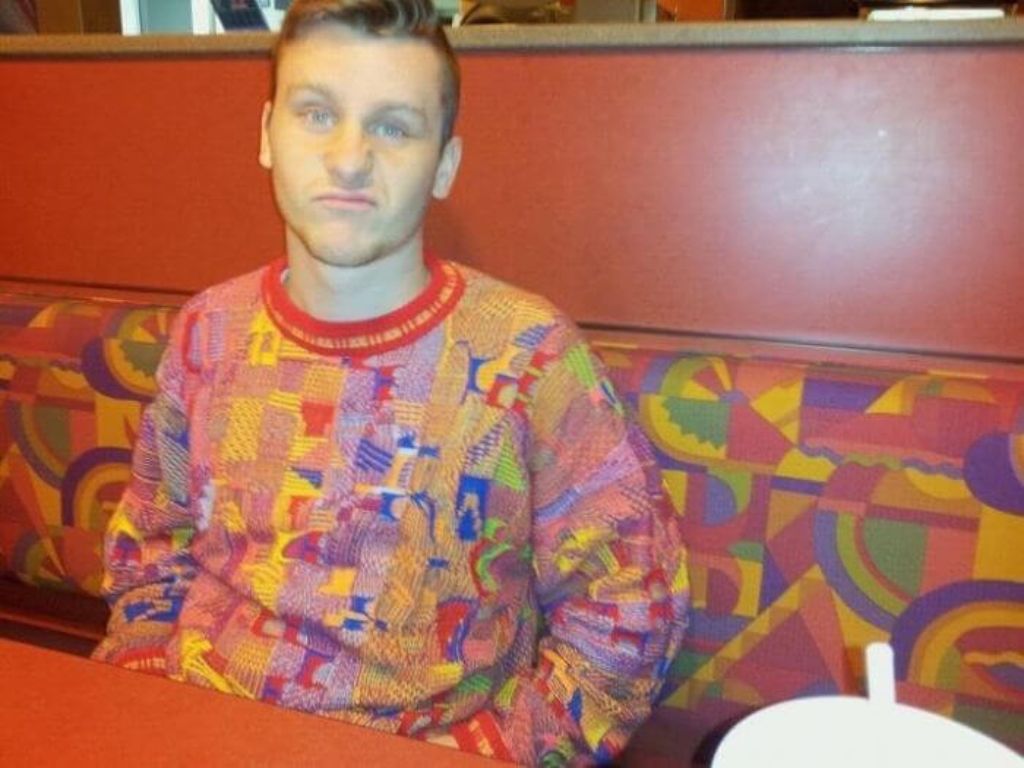 A man wearing a sweater that looks like the couch pattern behind him