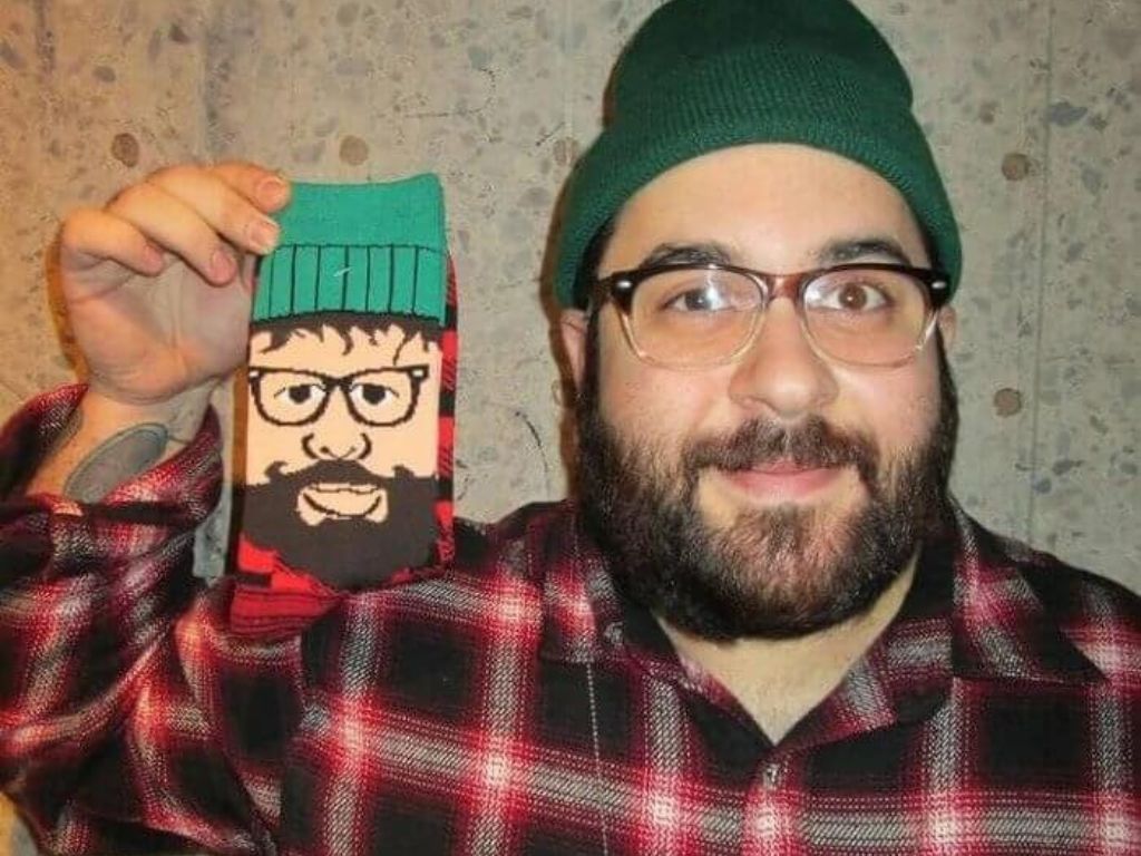 A man holding up a pair of socks that looks like him