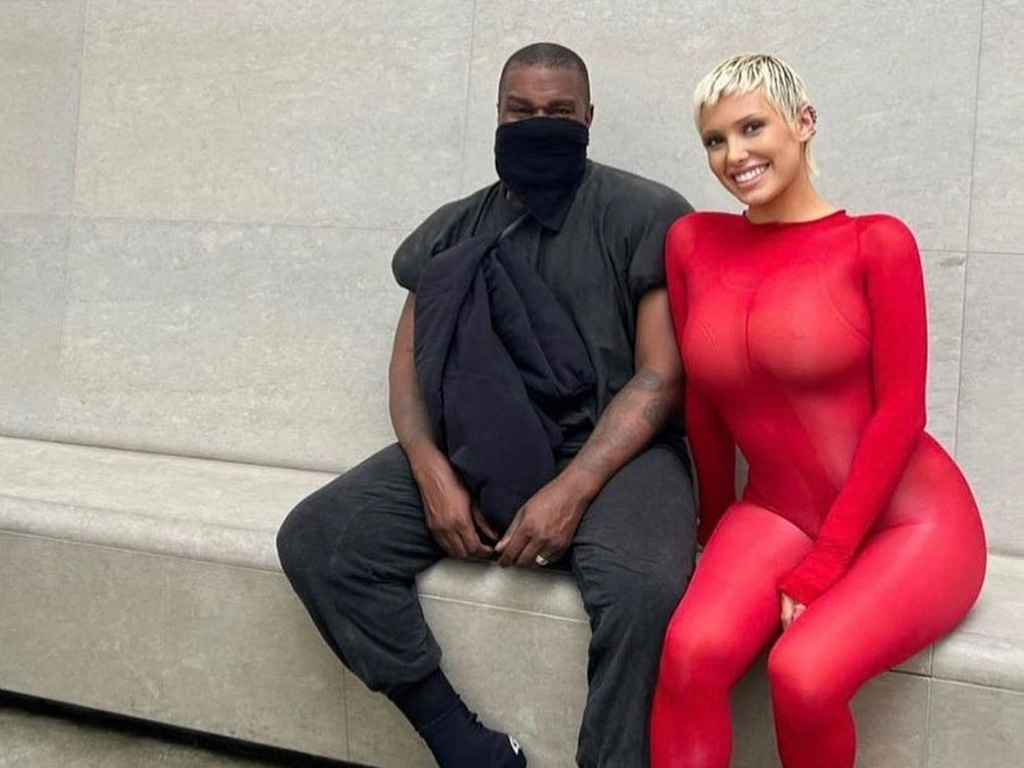 Kanye West wearing black and Bianca Censori wearing red.