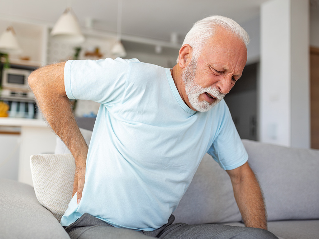 A man having back pain white sitting on a couch