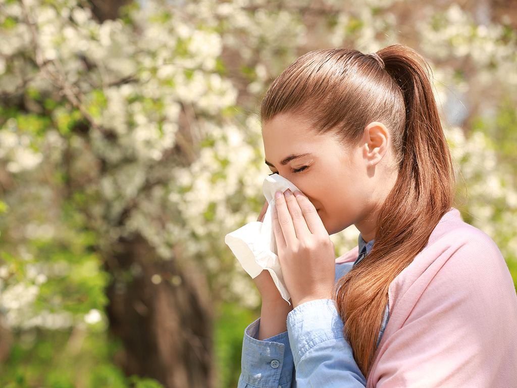 A woman sneezing in front of plants