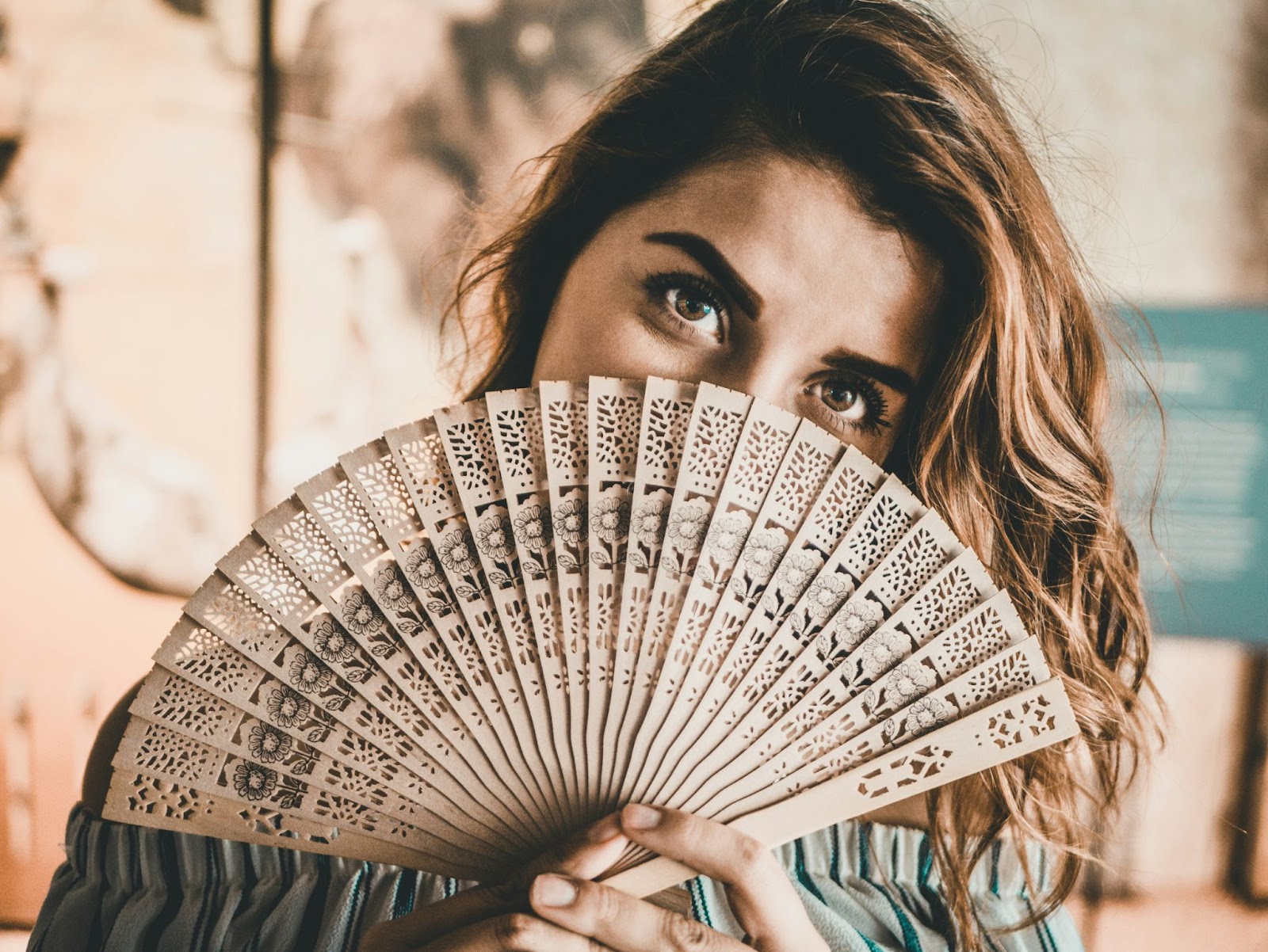 Woman holding a folding fan in front of her face