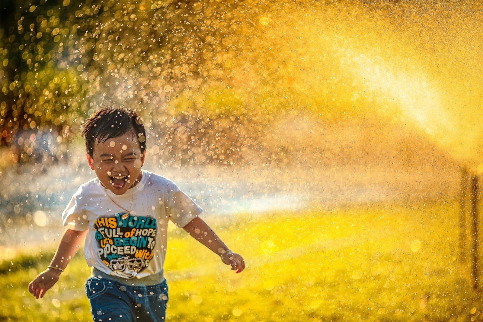 A child running through sprinklers while smiling 