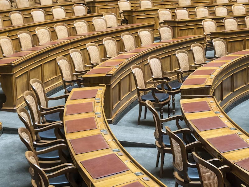 Rows of chairs around a long table in a government building