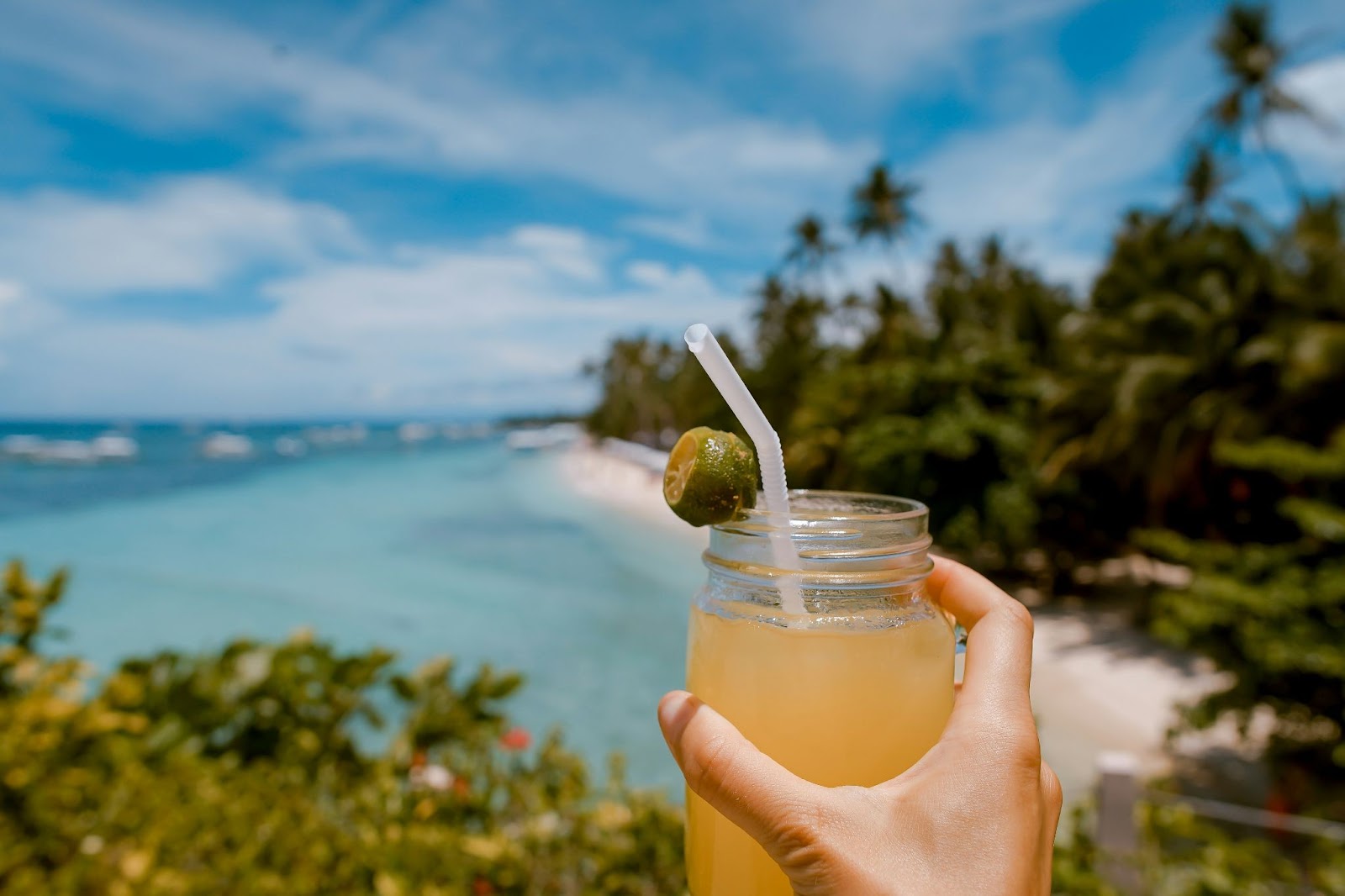 Cool beverage with lime on the rim in front of a beach landscape