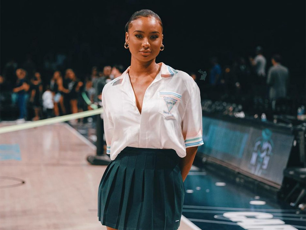 Kayla Nicole wearing a green skirt and white shirt on a basketball court