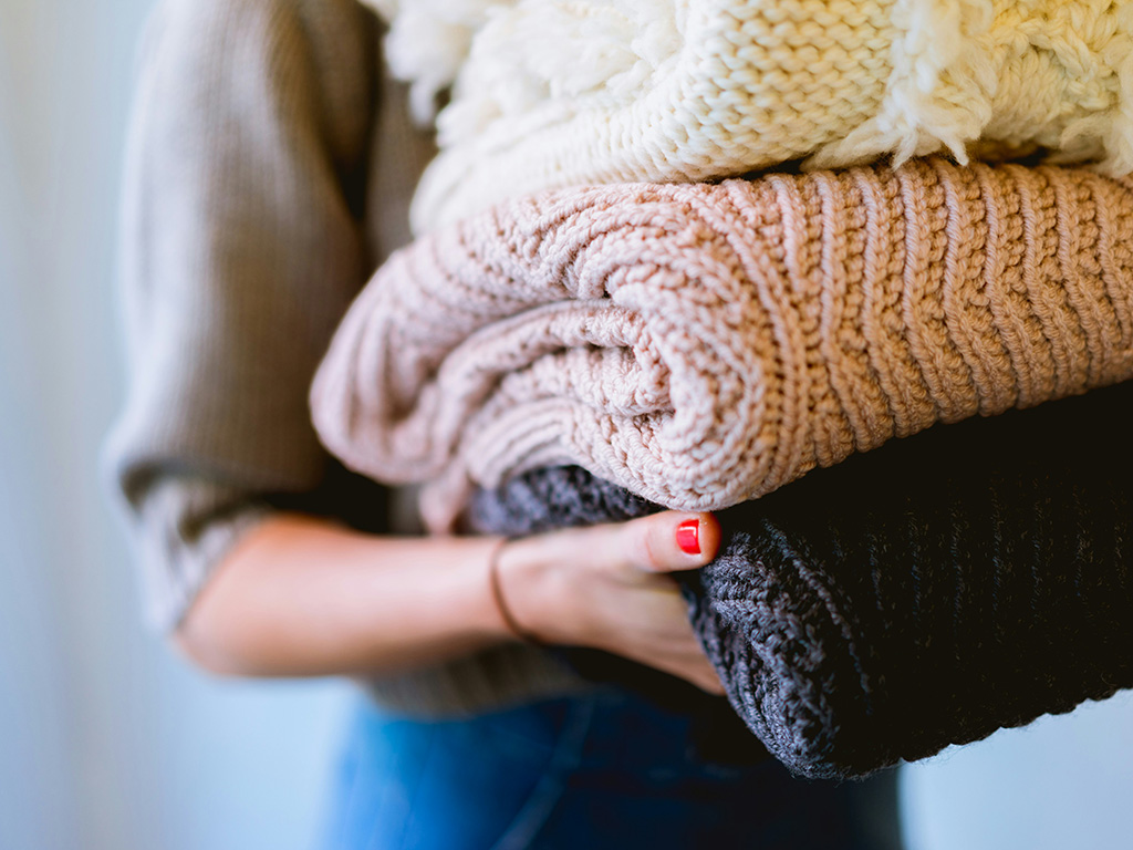 Woman carrying three fluffy blankets