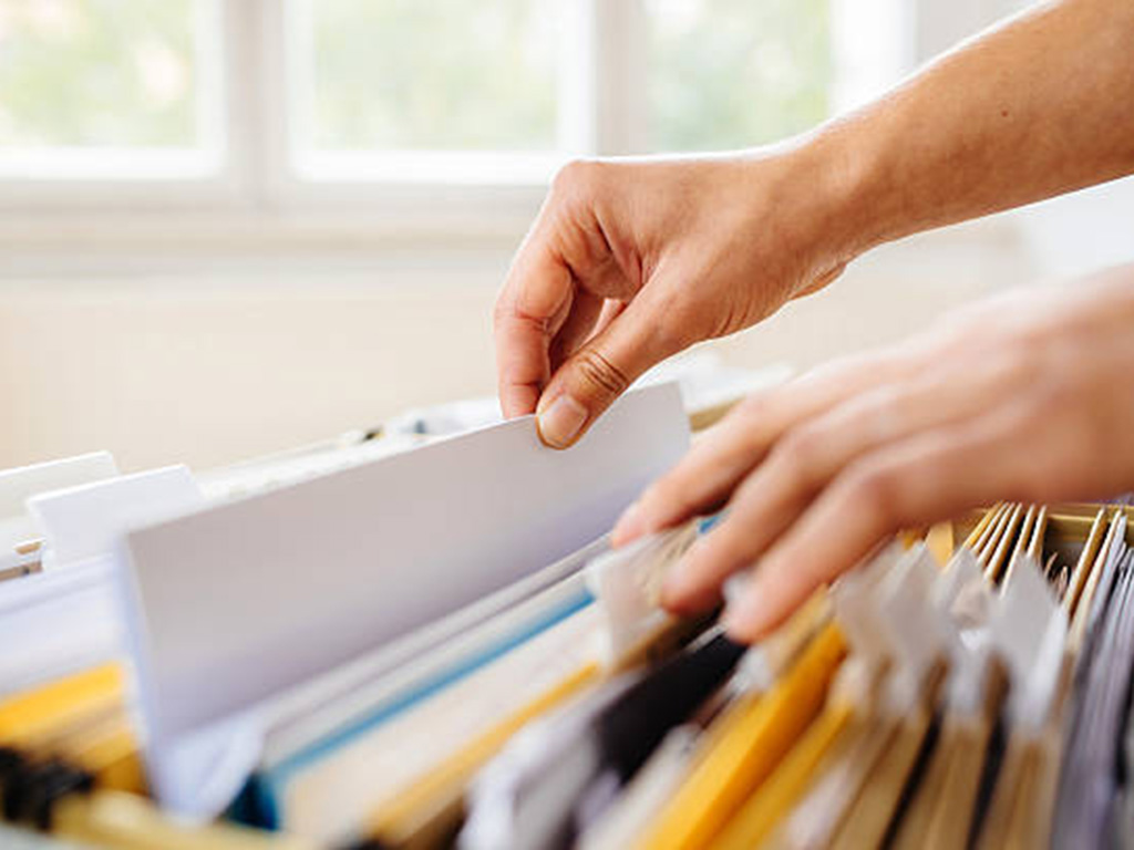 Hands going through papers in a filing cabinet