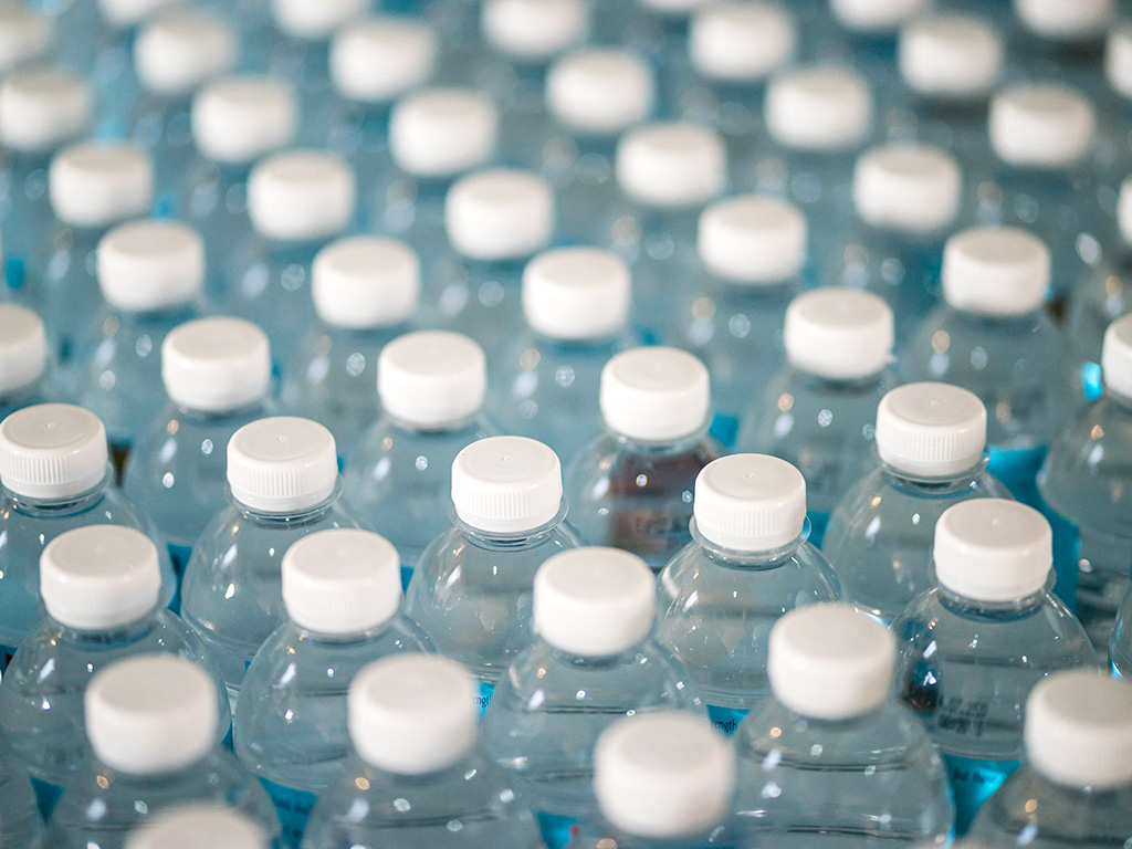 Rows of full plastic water bottles with white caps.