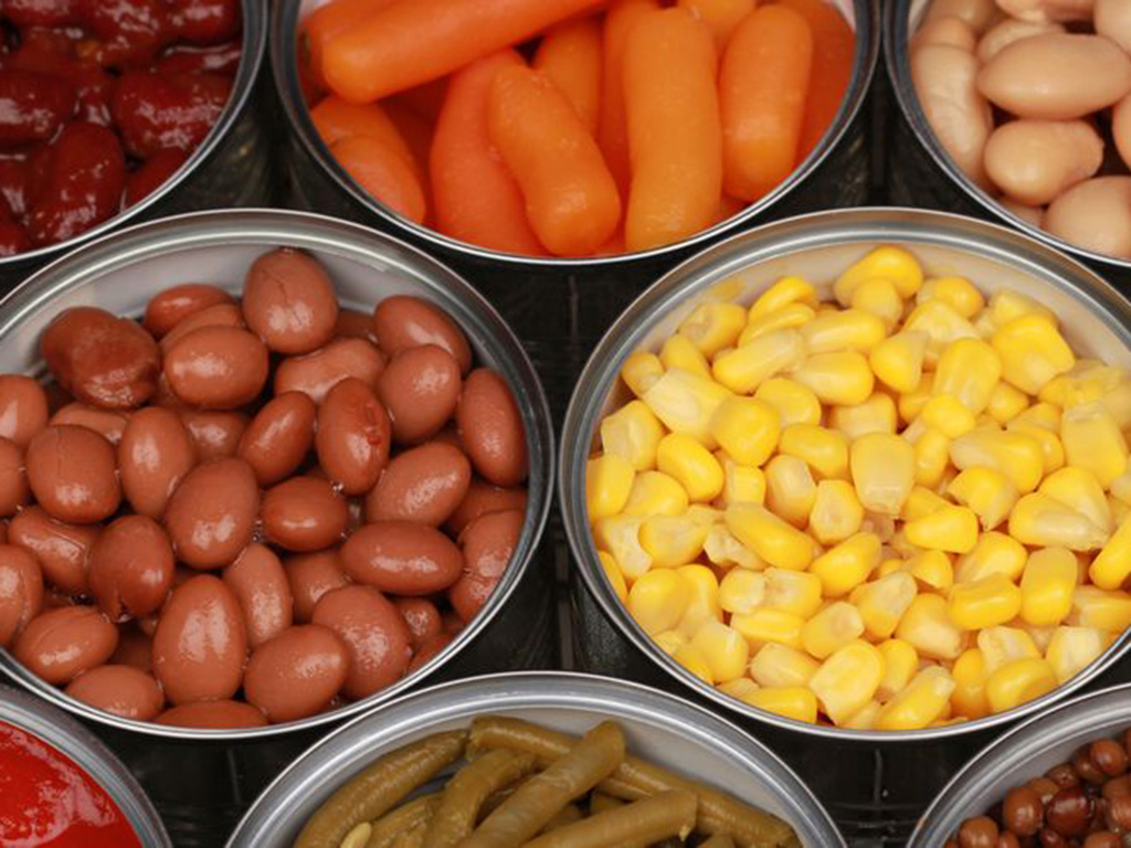 Several opened cans of canned food including beans, corn and carrots.