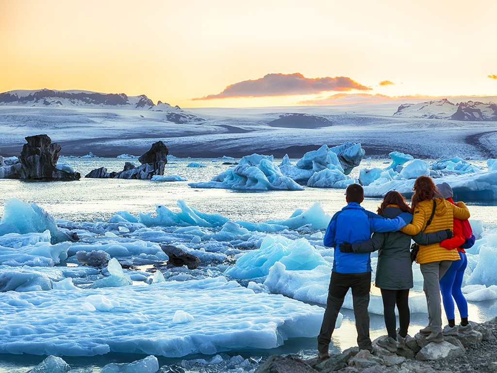 A group of people in puffer jackets looking at small glaciers