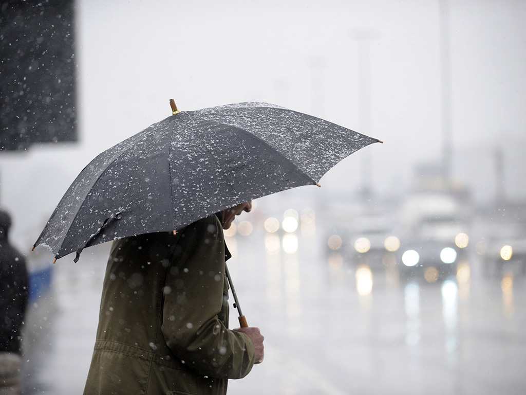 Person in a trench coat holding an umbrella in the rain