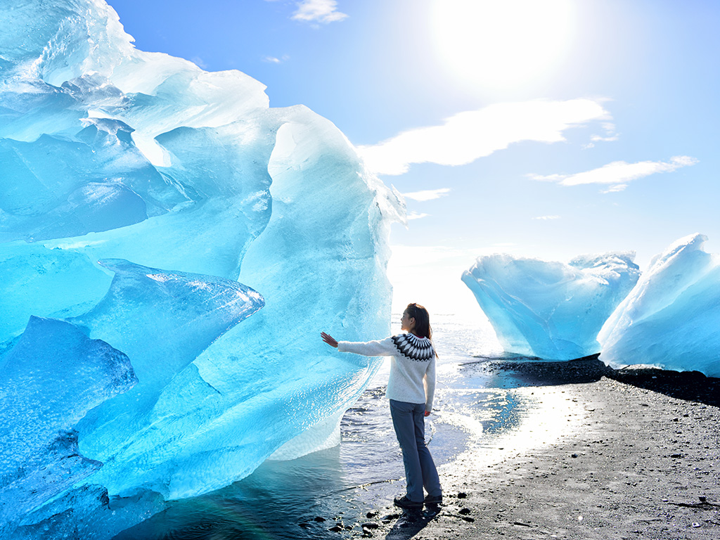 A woman in a sweater touching a glacier