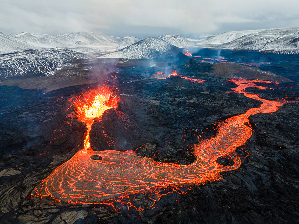 Icelandic volcano in front of snow-topped mountains