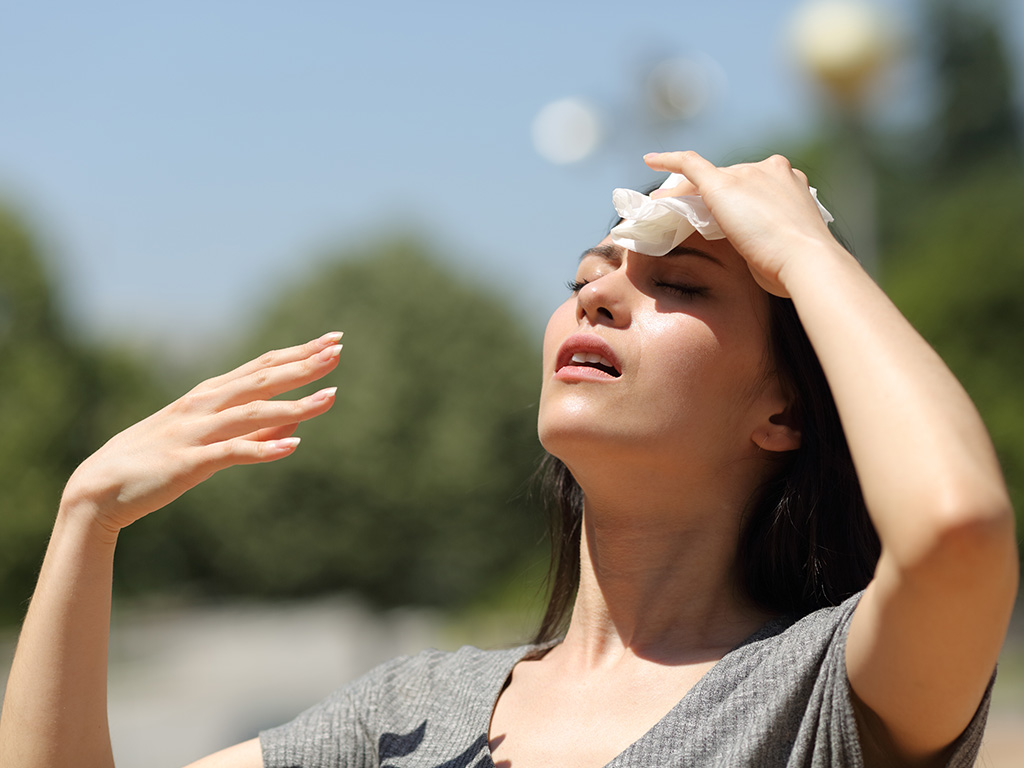 Stressed asian woman drying sweat with a cloth in a warm summer day