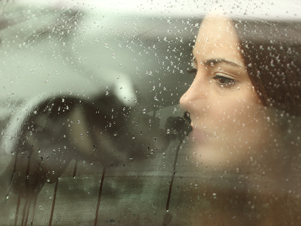 Sad woman or teenager girl looking through a steamy car window