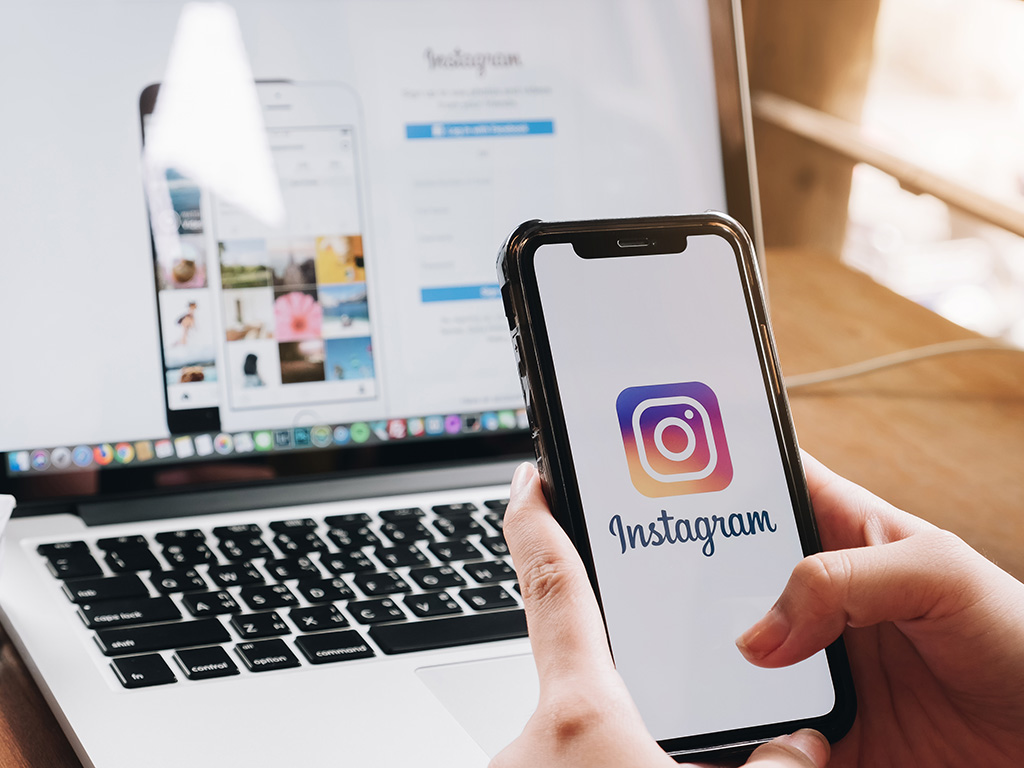 A woman holds Apple iPhone X with Instagram application on the screen at cafe. 