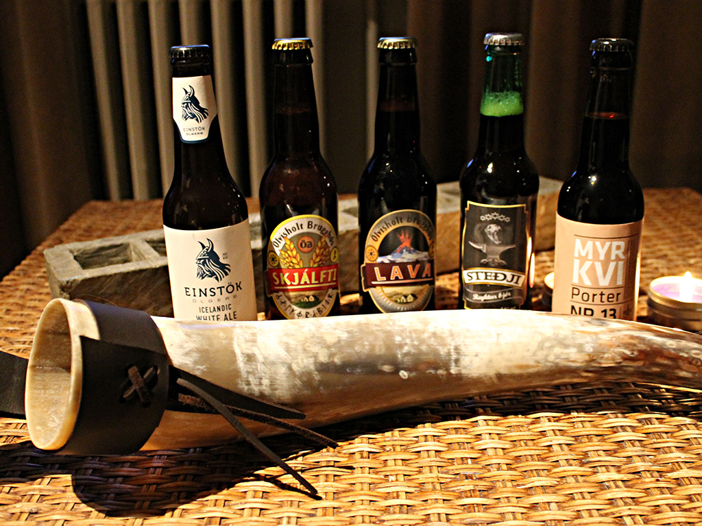 Several bottles of Icelandic beer and a drinking horn displayed on a straw table