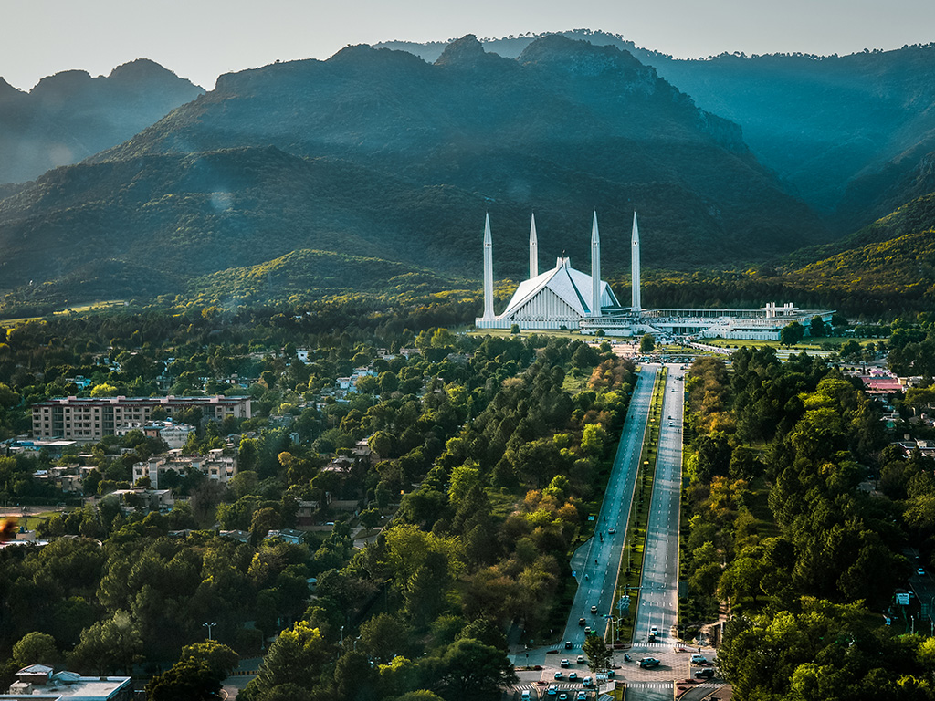 Aerial photo of Islamabad, the capital city of Pakistan showing the landmark Shah Faisal Mosque and the lush green mountains of the city