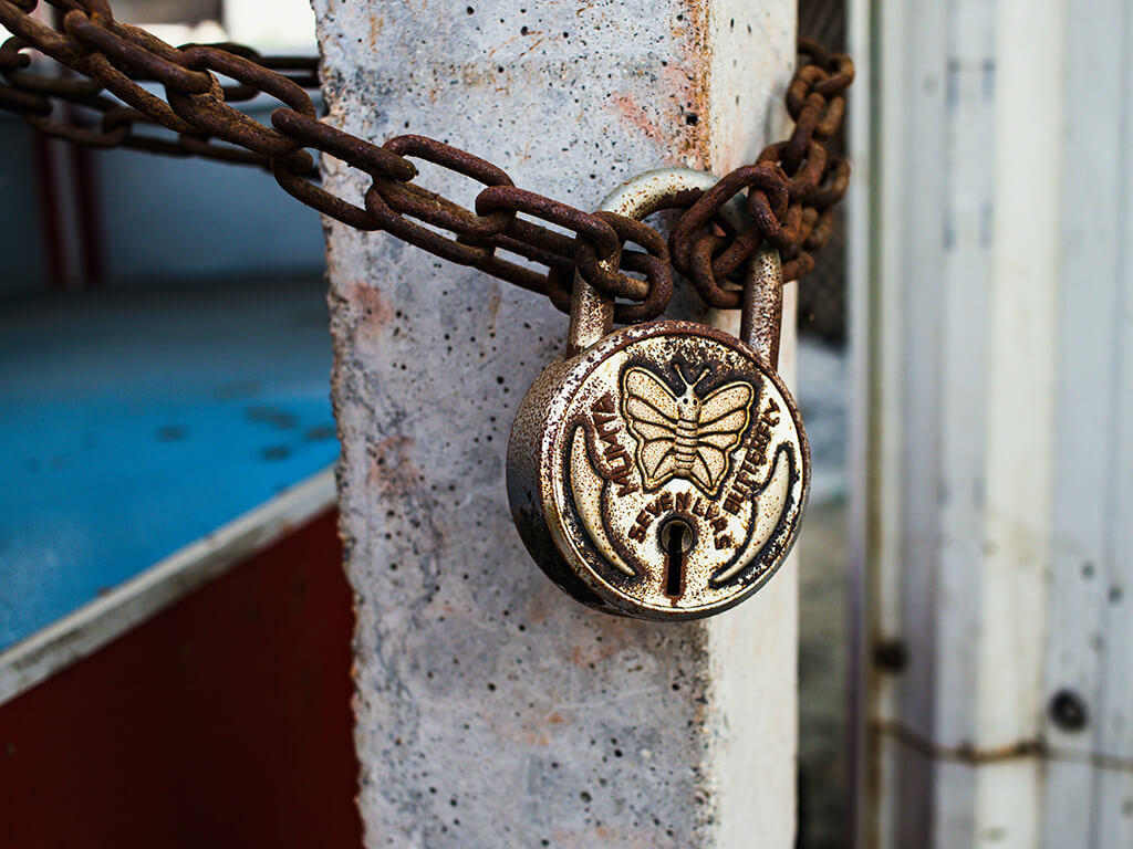 A close up of a padlock on a rusty chain