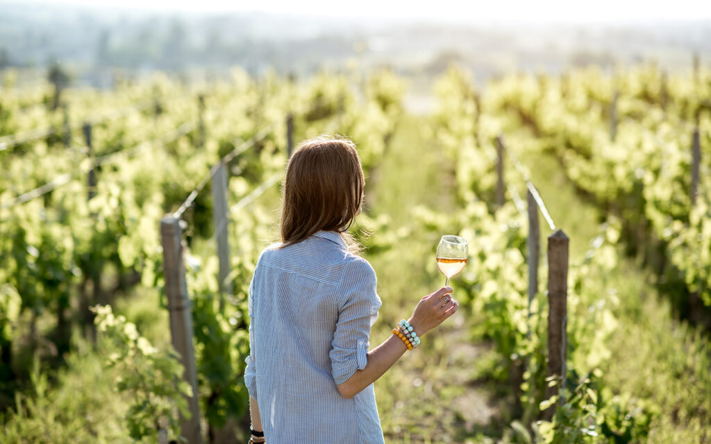 Woman standing in a vineyard with a glass of wine