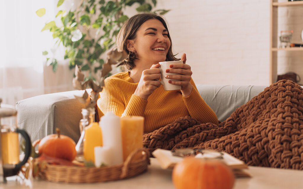 Woman enjoying hot beverage on couch with blanket